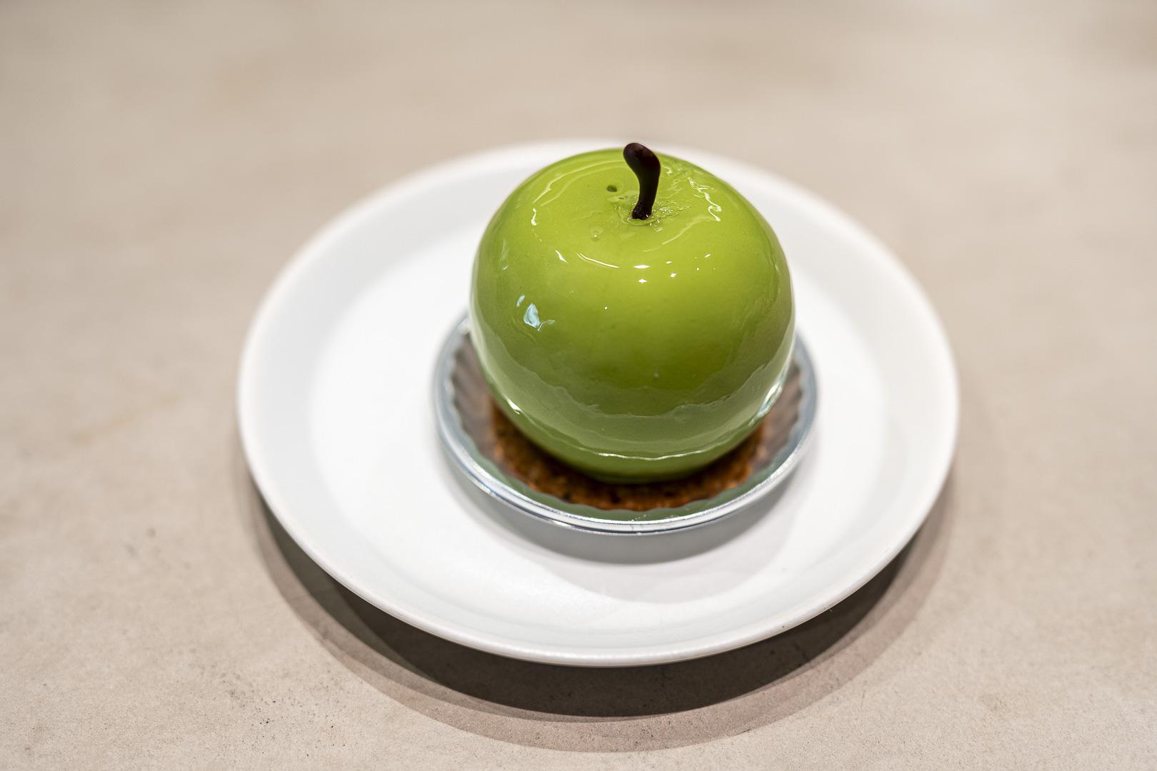 hannoc cake cafe: A green apple-shaped dessert on a white plate.