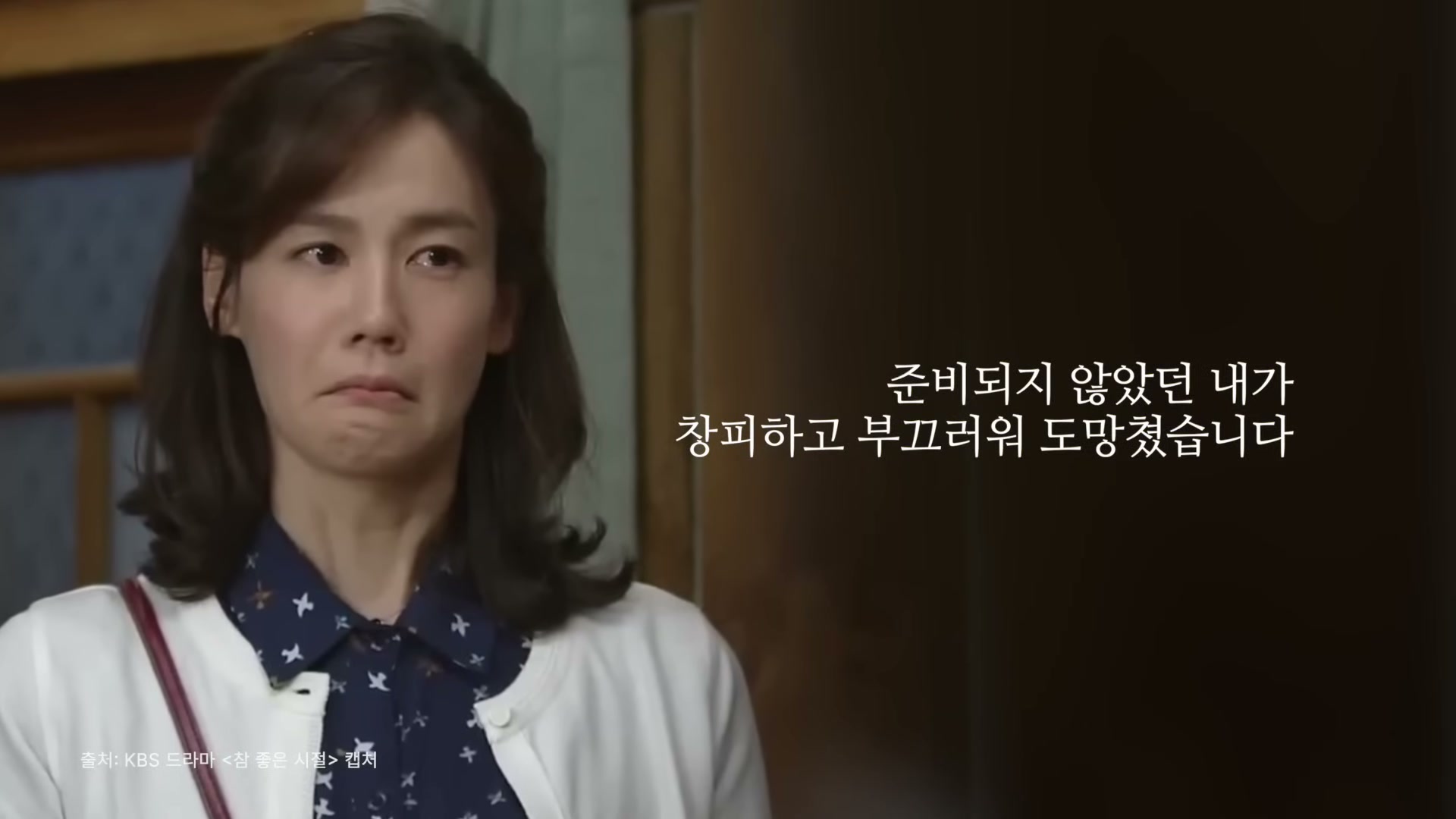 파란 셔츠와 흰 카디건을 입은 김지호가 입을 다물고 정면을 바라보는 드라마 한 장면