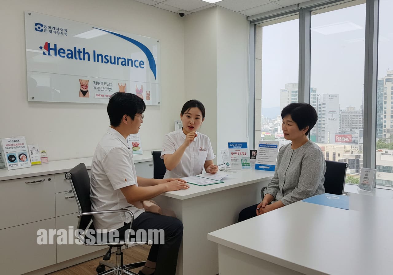 한국인 보험 상담원이 환자에게 실손보험이 체중 감량 프로그램을 어떻게 보장할 수 있는지 설명하는 장면. 현대적인 사무실 안에서 환자는 테이블에 앉아 있고, 상담원은 서서 설명하며 도시의 전망이 보이는 창문을 배경으로 한다.