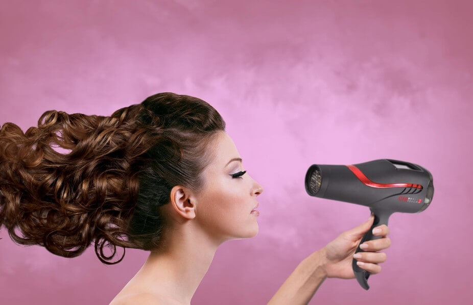 분홍색 배경으로 머리를 말리는 여성