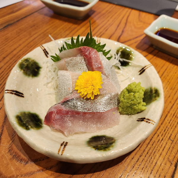 잿방어회 위에 노란꽃이 올려져 있다.