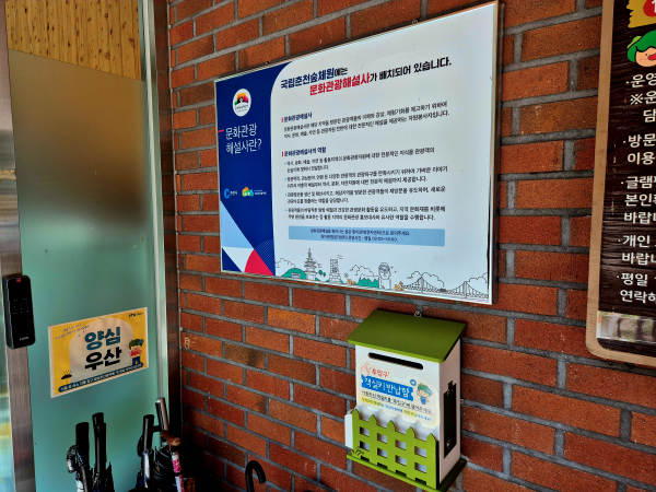 양심우산과 문화관광해설사 안내문, 산림복지서비스 이용권함이 있는 풍경