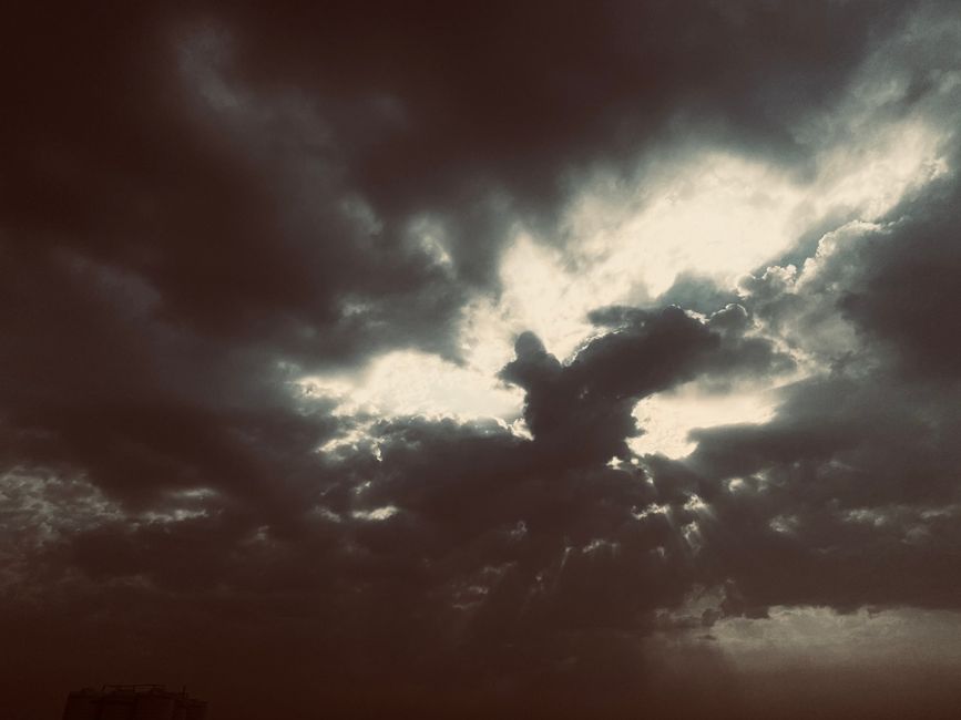 A dramatic view of dark clouds with sunlight breaking through, captured in New Delhi, India.