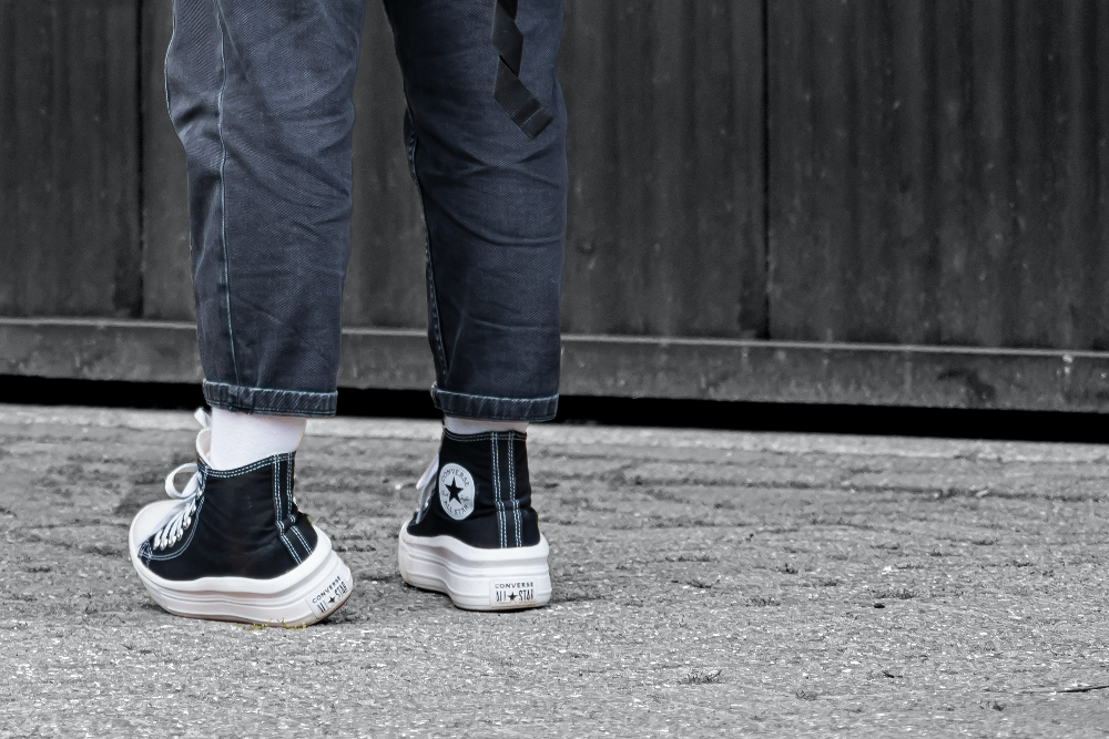 검은색 스니커즈를 신은 사람의 다리와 발이 보이는 사진