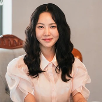 흰 블라우스를 입고 검은 웨이브 머리를 하고 앉아 있는 드라마 열녀박씨 계약결혼뎐의 강해령 캐릭터