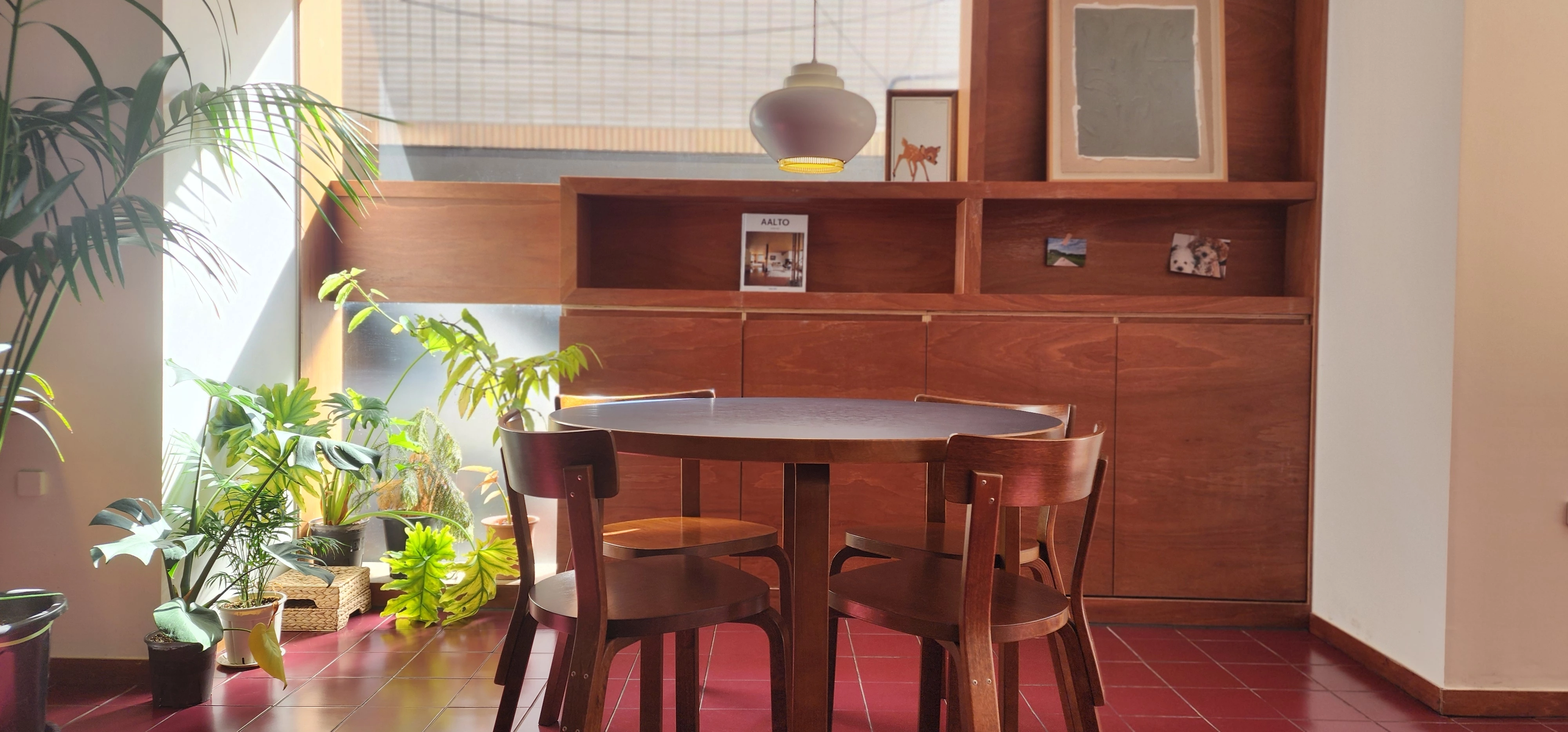 카페 내부, 고풍스러운 테이블과 전등, 주변의 녹색식물, 불투명창으로부터 들어오는 산란된 겨울햇빛