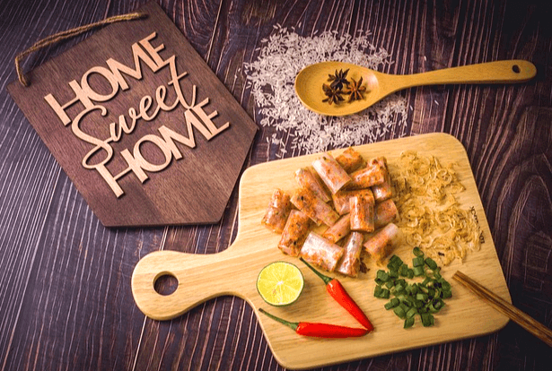 나무 식탁 위에 쏟아진 하얀 쌀이 있다. 나무 쟁반엔 잘려진 소시지조각들이 가득하다.