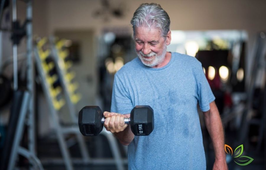 헬스장에서 덤벨을 들고 근력 운동을 하는 중년 남성, 중년 운동과 근력 트레이닝의 중요성을 보여주는 이미지 via canva