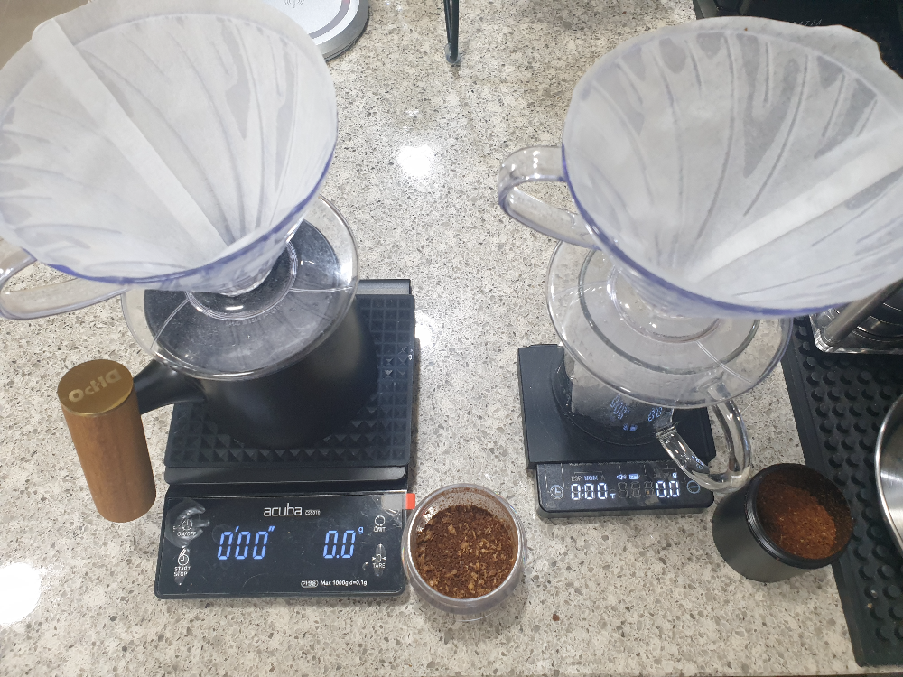 두 개의 저울위에 각각 서버와 드리퍼가 올려져있다. 각 저울 우측에는 그라인더로 분쇄한 원두가 담겨있다.