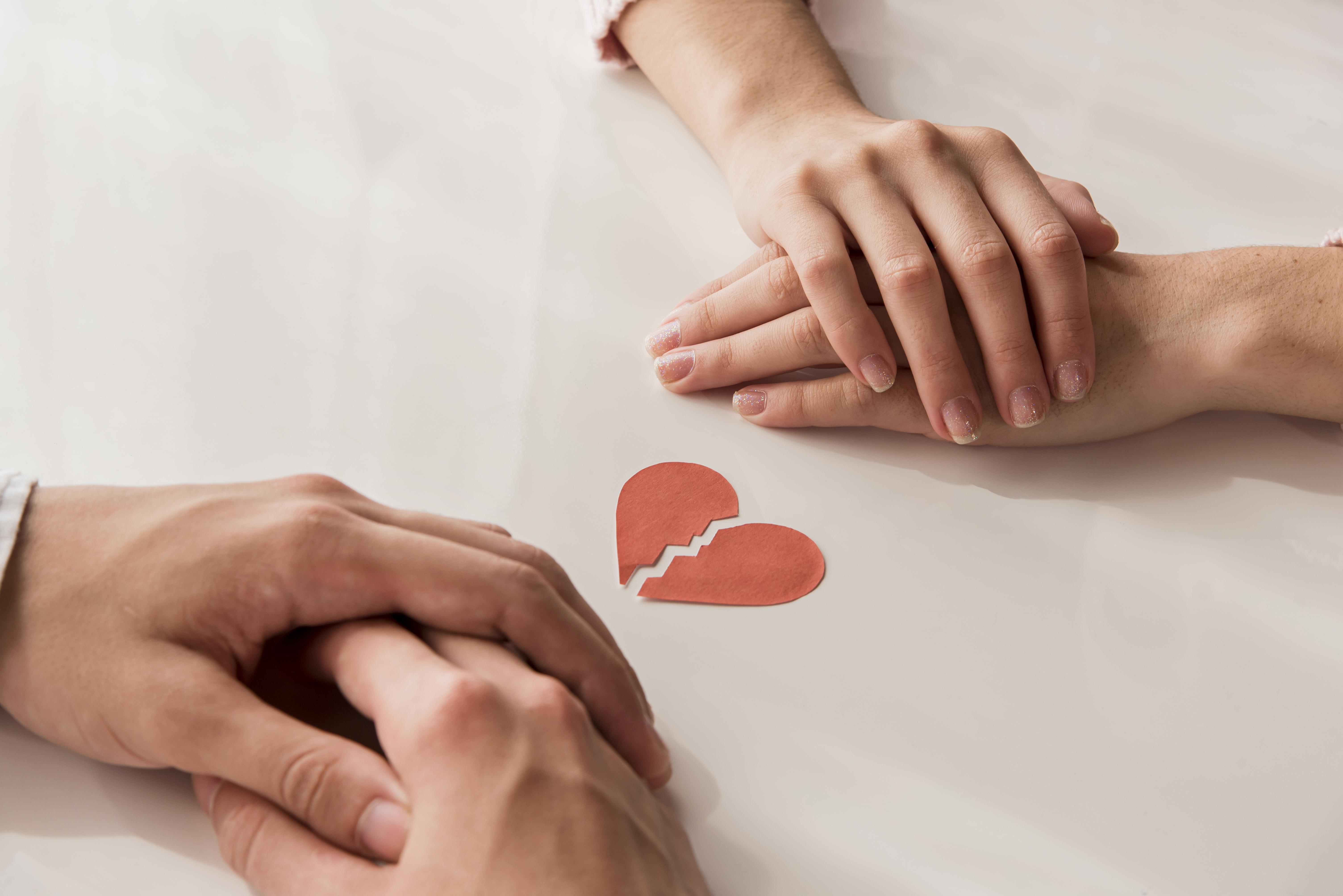 이혼을 앞둔 부부가 합의 없이 감정적으로 갈등하는 상황을 상징하는 손잡기와 찢어진 하트 이미지