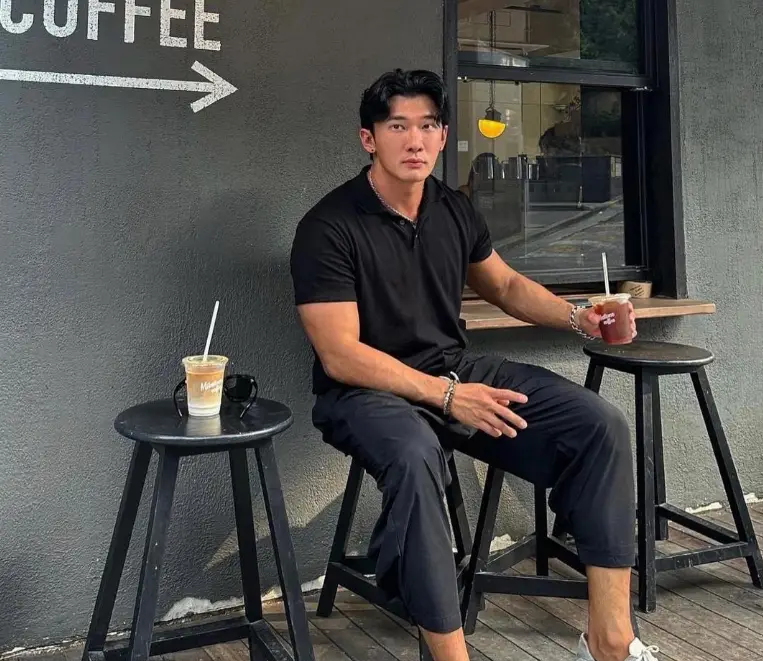 솔로지옥 3- 커피숍 야외 테이블에 검은색 의자에 앉아 검은 바지에 검은색 반팔티를 입고 왼손에 쥬스를 든채로 정면을 바라보는 이진석
