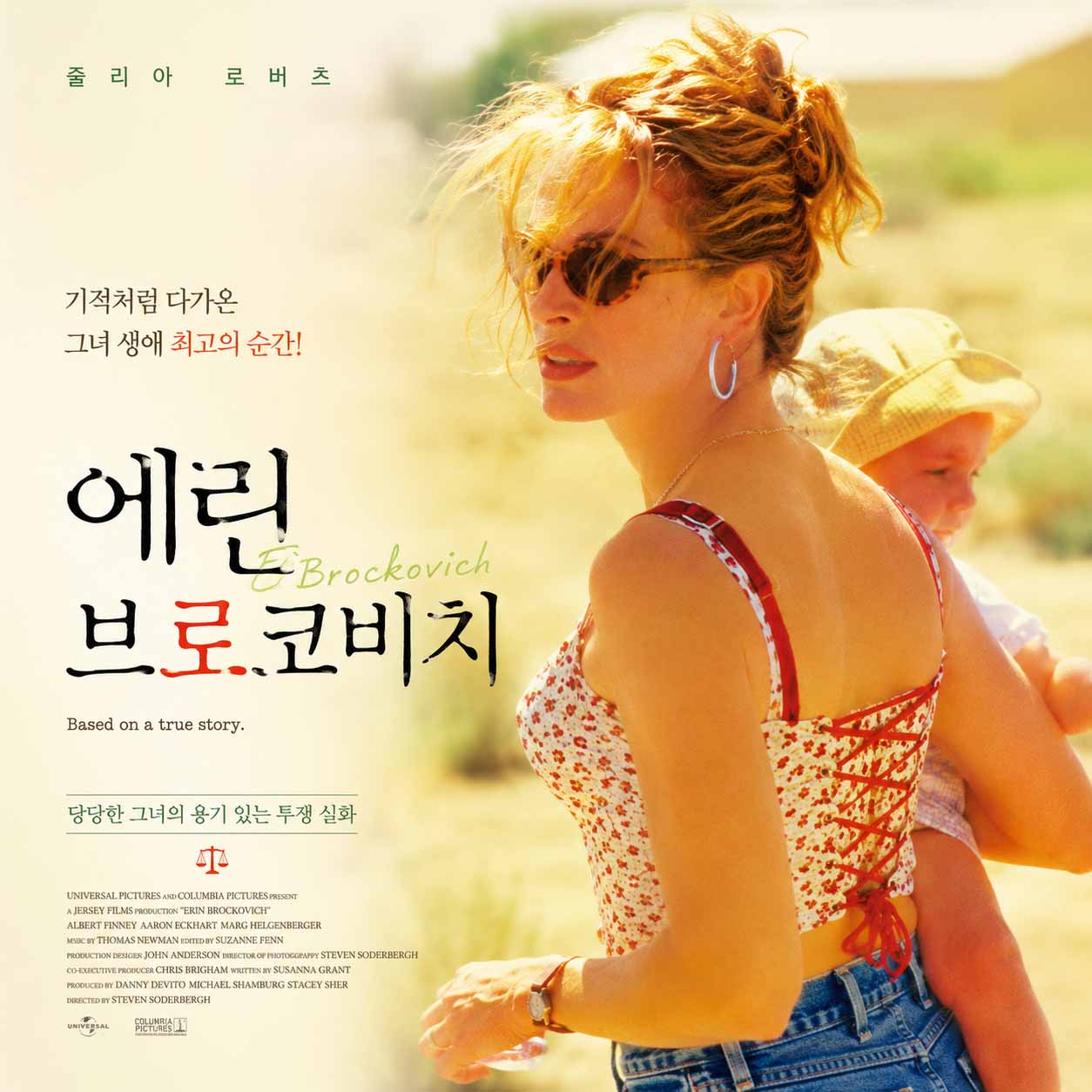 줄리아 로버츠가 선글라스를 쓴 채 아기를 안고 뒤돌아보는 영화 《에린 브로코비치》 포스터. 밝은 황금빛 배경 위에 영화 제목과 '당당한 그녀의 용기 있는 투쟁 실화' 문구가 적혀 있다.