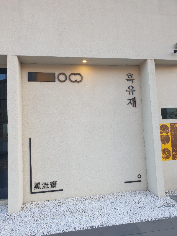 흑유재라고 쓰인 글이 부착되어 있는 콘크리트 회색 벽면