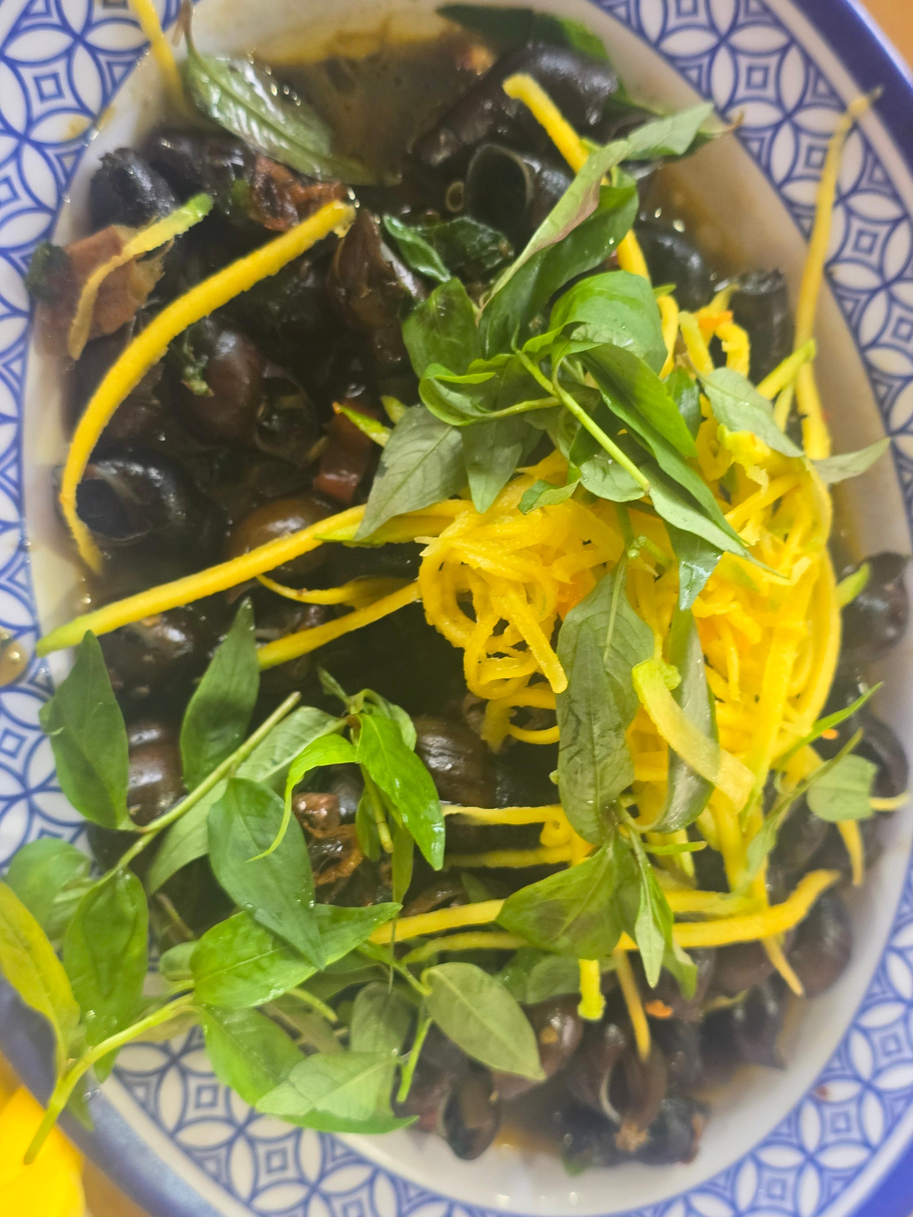 베트남 달팽이 요리 옥 노란 코코넛 채와 허브를 곁들인 접시