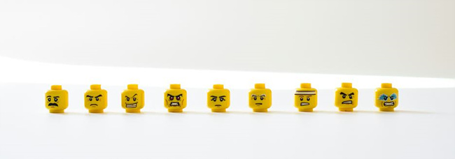 다양한 표정이 있는 레고 얼굴 모형들이 가로로 정렬되어 있는 사진
