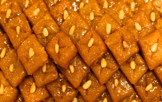 네모난 약과들이 한가득 있다. 갈색 약과이고 위에는 노란 잣이 한개씩 있다.