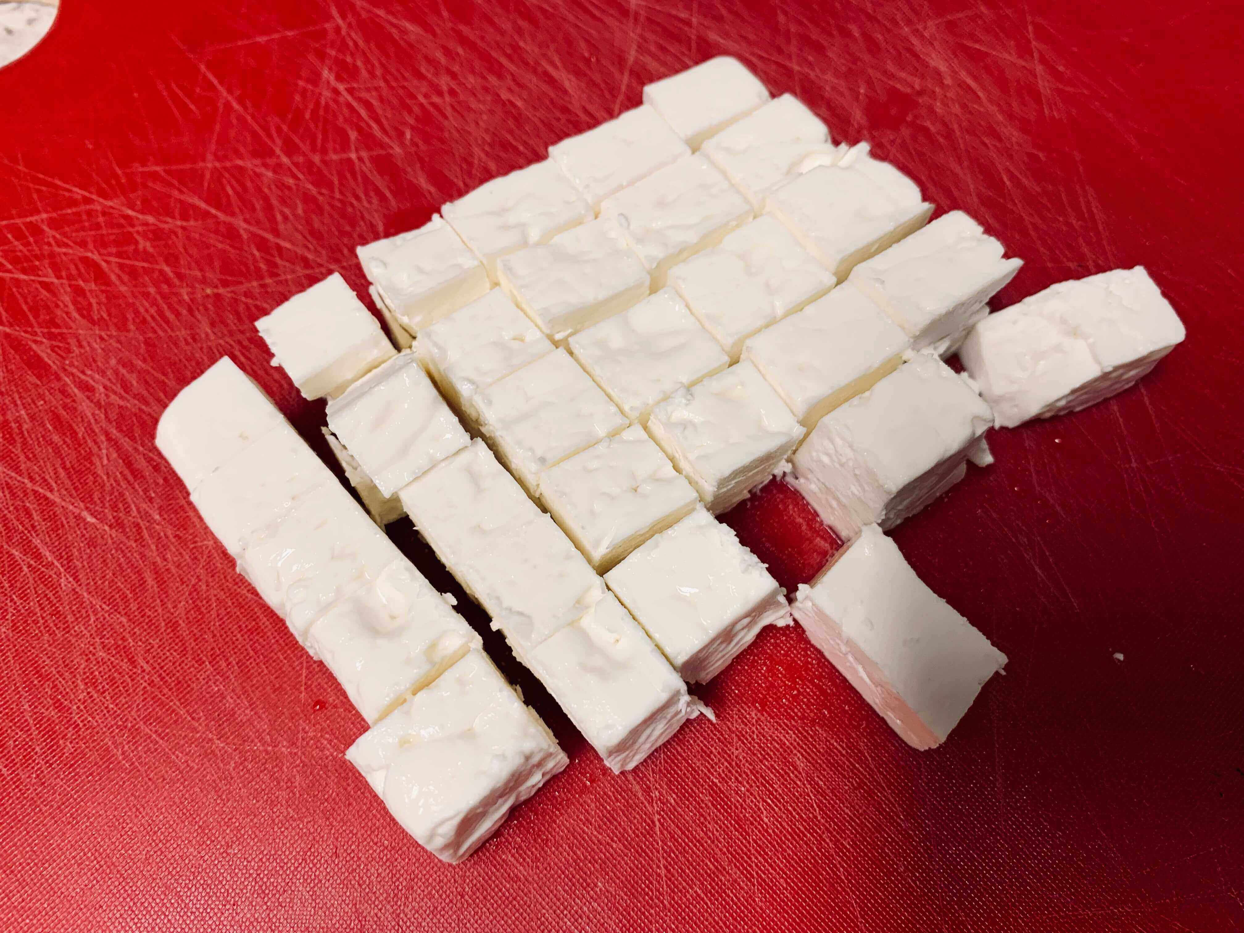 빨간-도마-위에-흰색-큐브모양-치즈가-썰린-모습