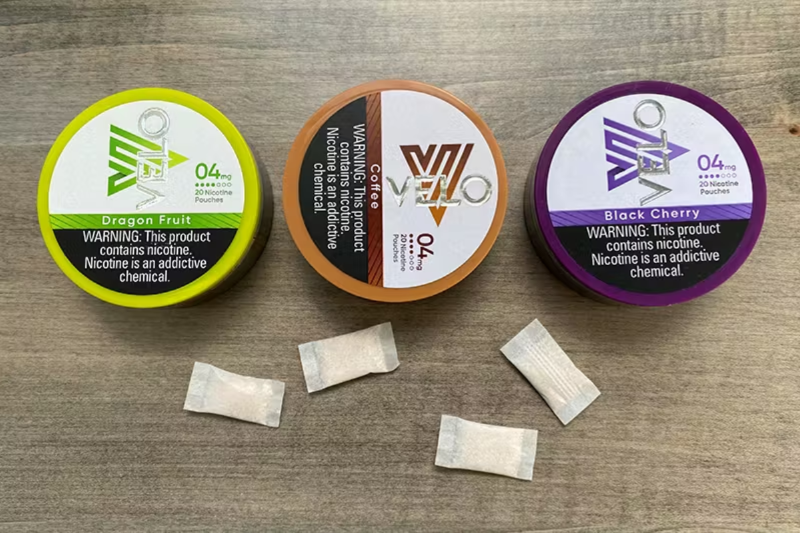 다양한 맛(드래곤 프루트, 커피, 블랙체리)의 VELO 니코틴 파우치 포장 이미지. 파우치 외형과 제품 경고 문구 포함