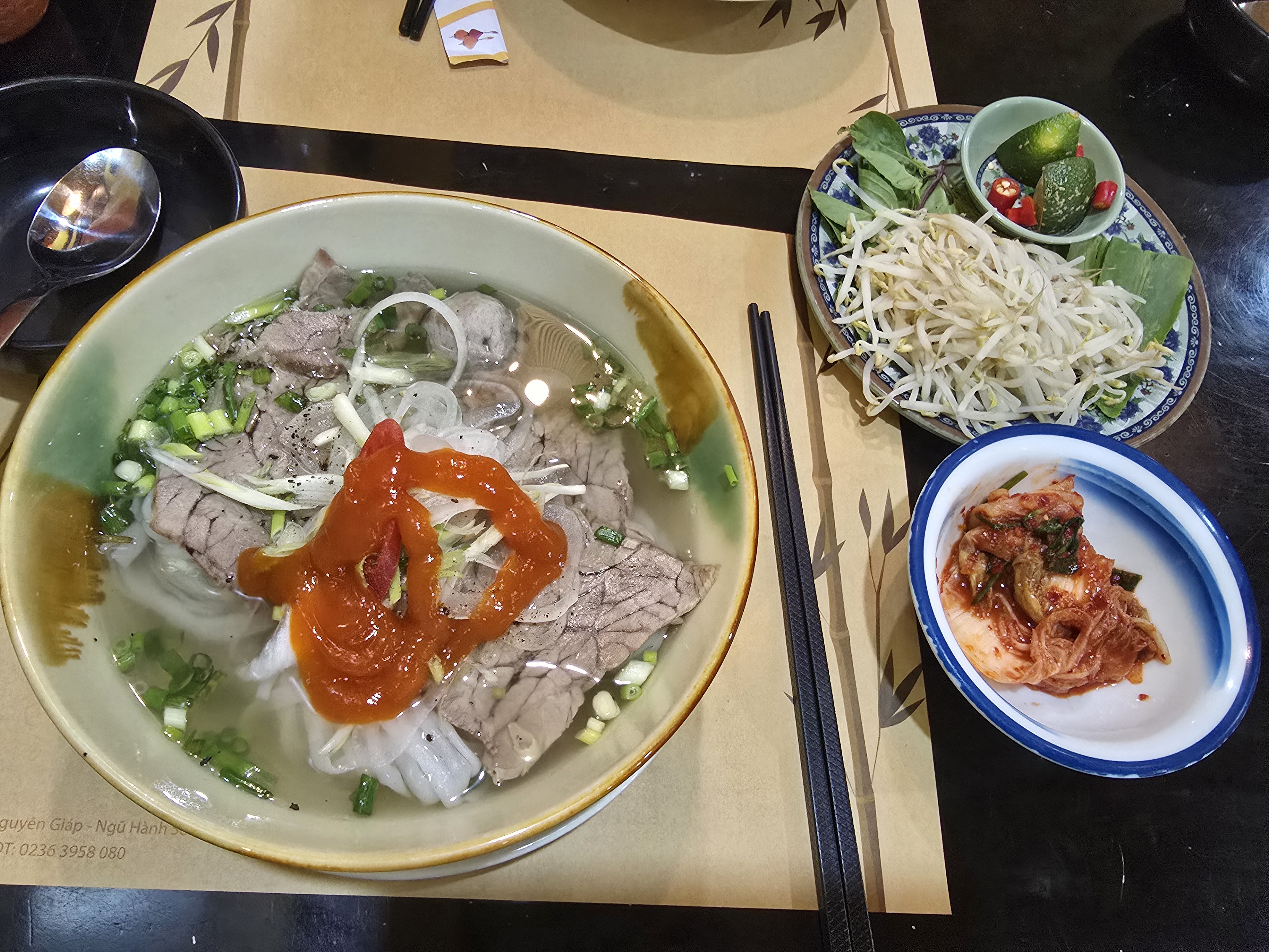 "따뜻한 쌀국수, 야채 접시, 한국식 김치로 가득한 밥상"