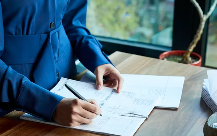 보험 설계서에 서명하는 사람의 손, 계약 내용을 신중히 검토하는 모습