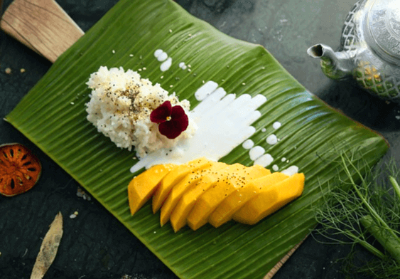 초록색의 네모난 바나나잎에 하얀 밥과 노란 망고가 있다. 밥위엔 자주색 꽃이 장식됐다.