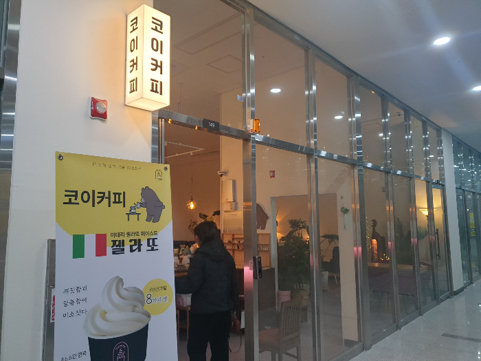 흰색 프레임에 전면 유리로 되어 있는 코이커피. 내부 조명은 은은한 주황색이다.