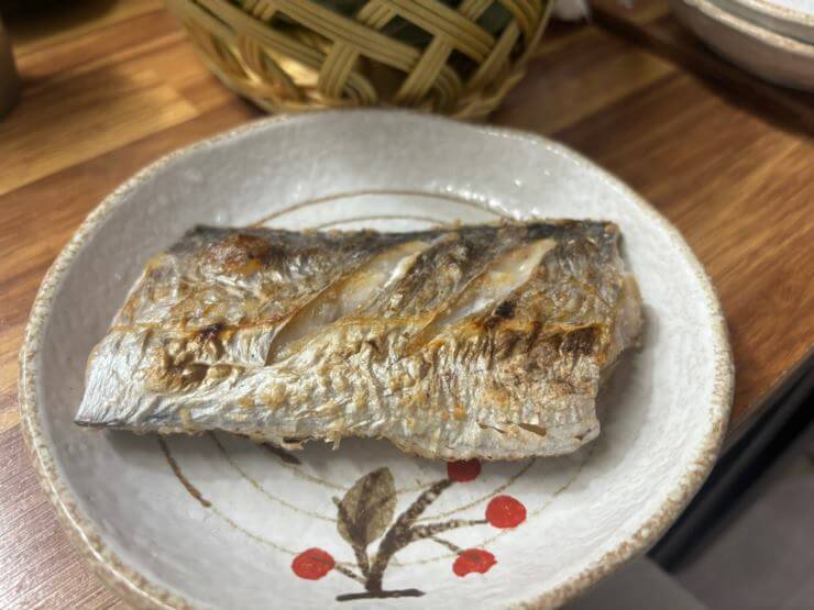 빨간 꽃이 그려진 연한 회색 접시 위해 갈치 한토막이 있다.
갈치 위에 칼집이 2개 가 있고 노릇한 색깔로 구워졌다.