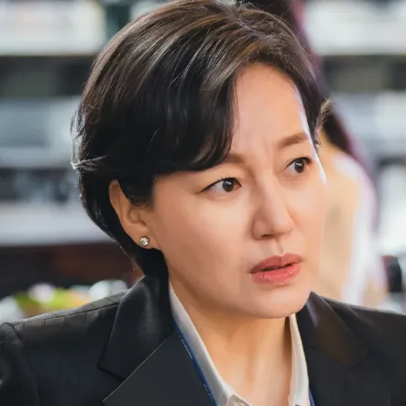 어느 실내를 배경으로 검은 정장을 입고 인상을 쓰고 있는 소용없어 거짓말의 차향숙