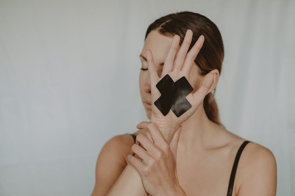 Young woman in black lingerie with closed eyes demonstrating hand with black tape cross against violence on white background
