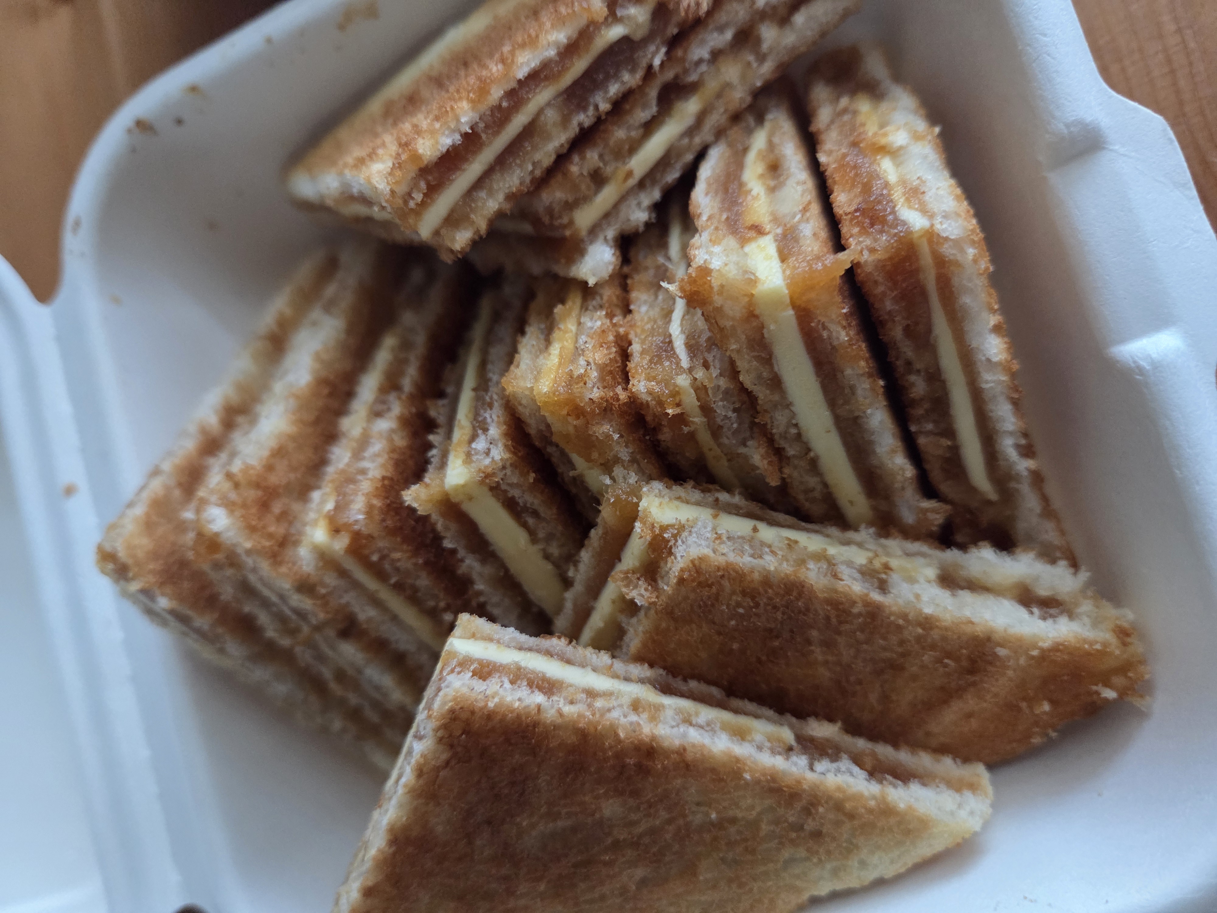 카페 어바웃미 카야토스트가 가지런히 담긴 포장 용기, 바삭하게 구워진 빵 사이로 버터와 카야잼이 보이는 모습