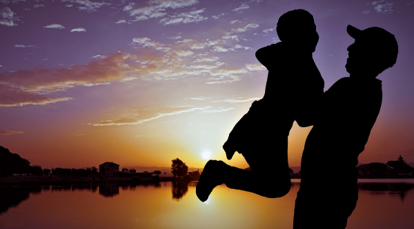 석양빛이 도는 노을 앞에 아이를 들어 올리는 아빠의 모습