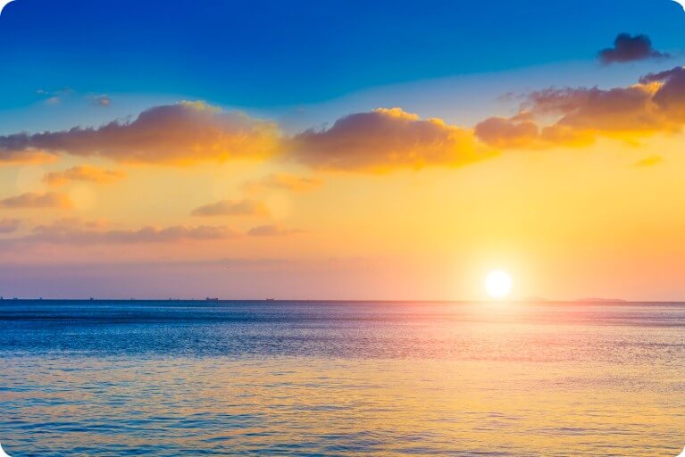 바닷가 넘어 해가 떠오르는 모습