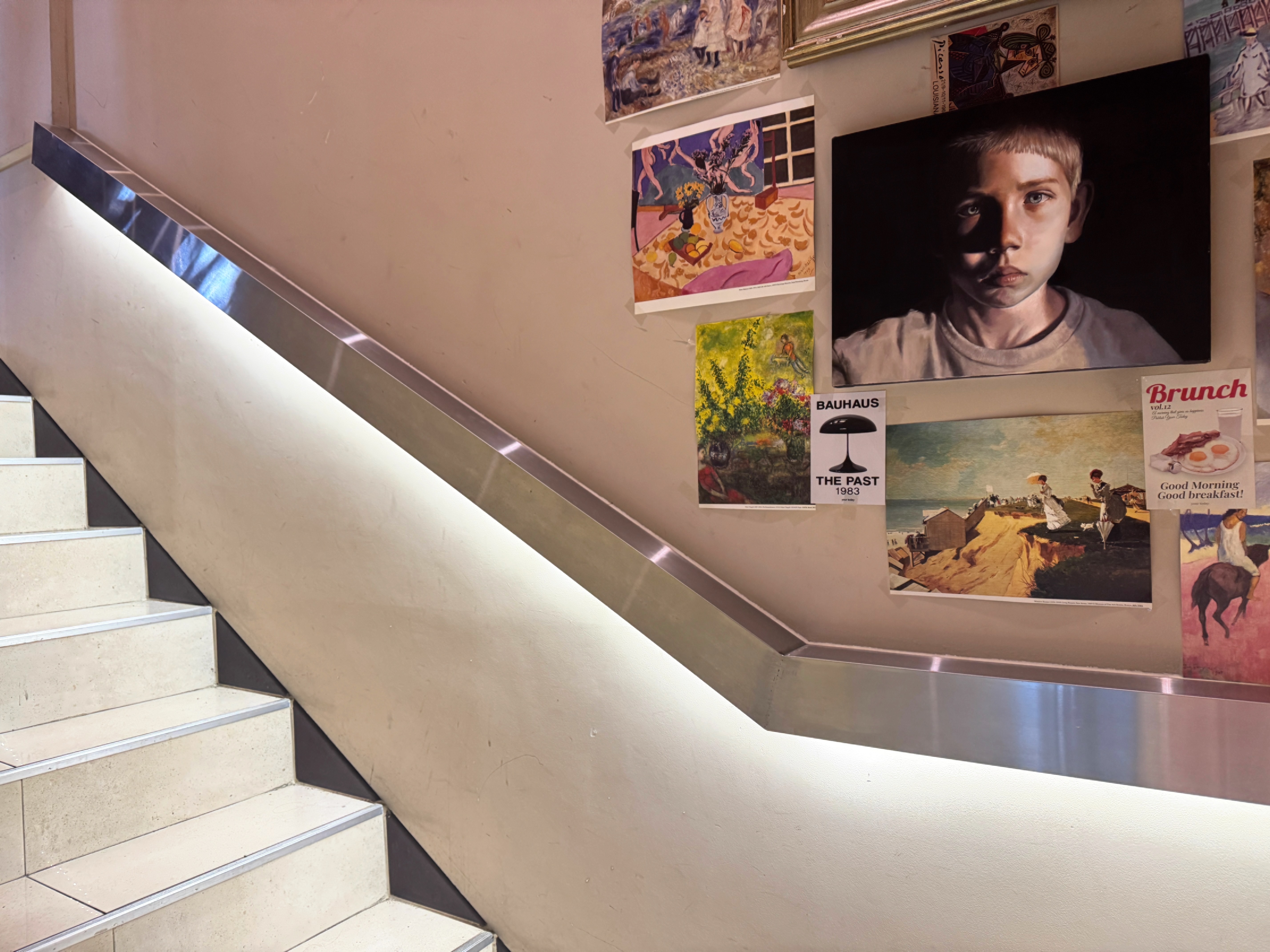 정자동 엑성프로방스 카페 2층 올라가는 계단 벽 &ndash; 다양한 그림과 포스터로 장식된 갤러리 같은 분위기