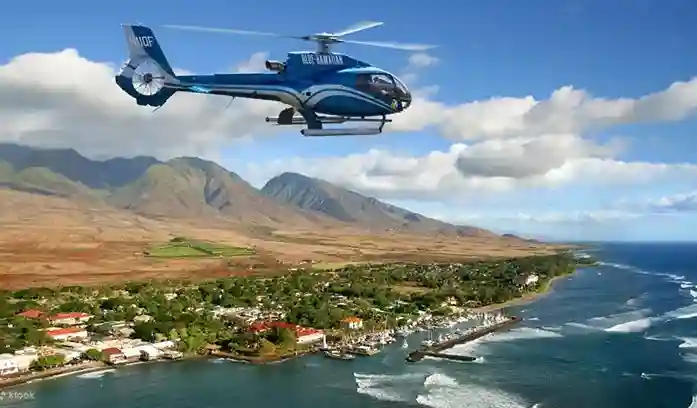 하와이 마우이 섬의 아름다운 해안선과 산맥 위를 비행하는 블루 하와이안 헬기 투어 사진. 푸른 바다와 맑은 하늘이 보인다.