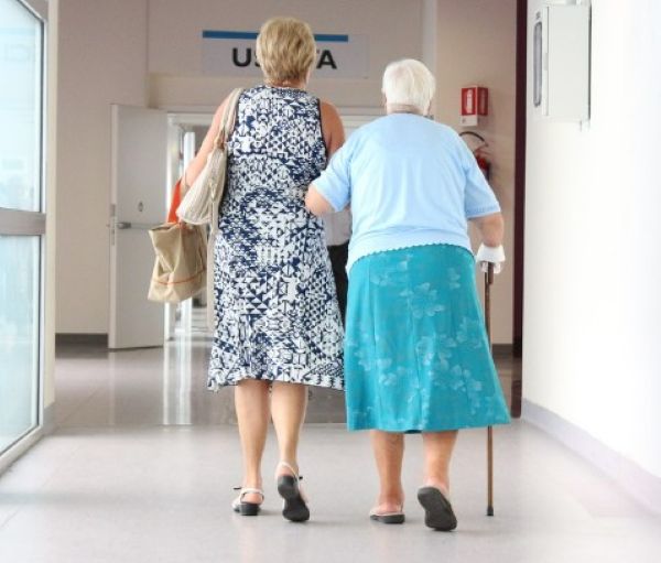 노인과 요양보호사가 병원 복도를 함께 걷고 있는 장면