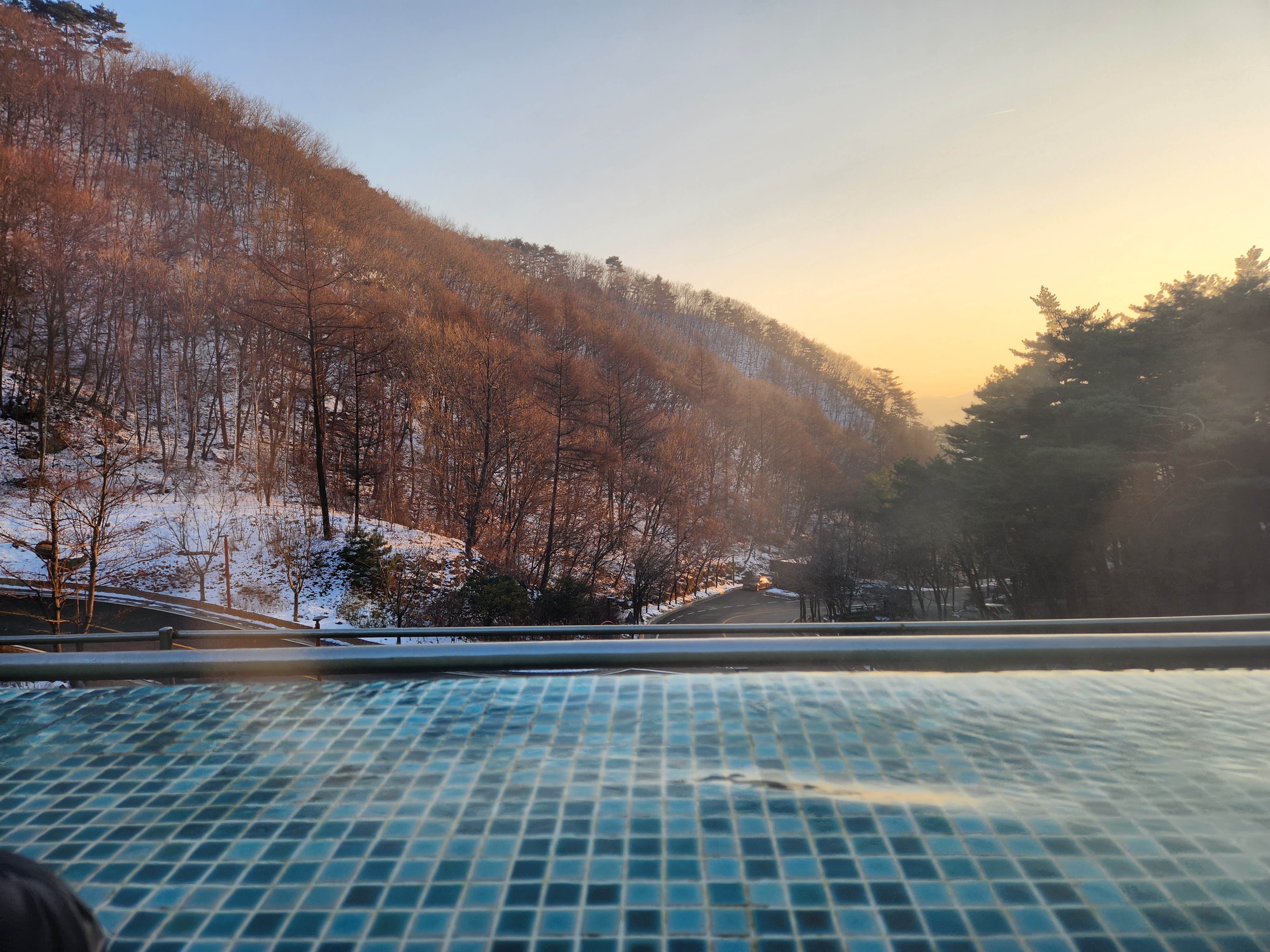 인피니티풀 앞쪽으로 눈 덮인 산과 노을지는 풍경