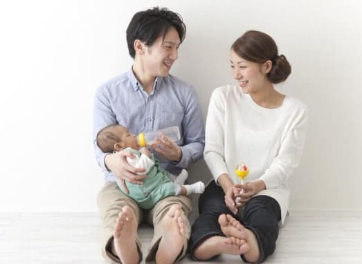 아기를 안고 있는 남자와 옆에 그모습을 바라보고 웃고 있는 여자