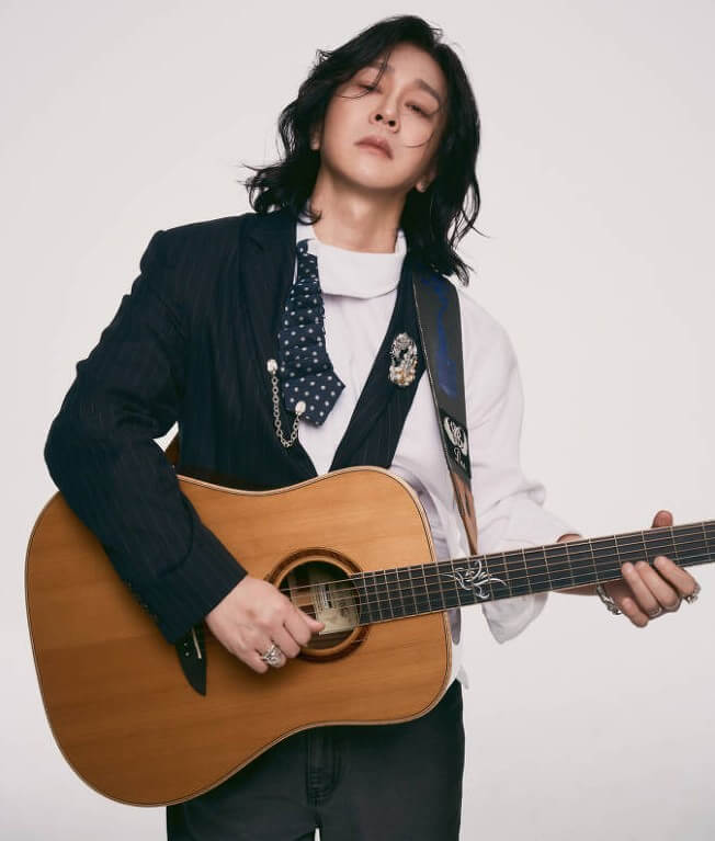 윤도현이-스모키-화장을-하고-기타를-메고-아래쪽을-응시하는-사진