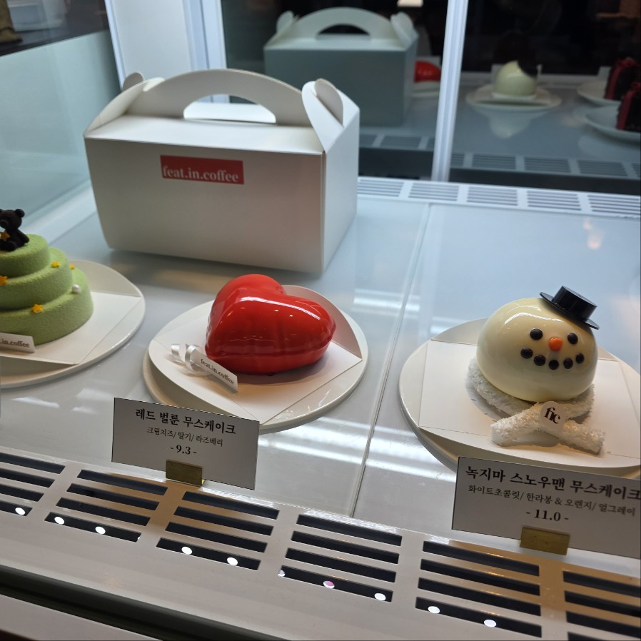레드 하트 무스케이크와 녹차 스노우맨 케이크가 함께 진열된 카페 디저트 쇼케이스