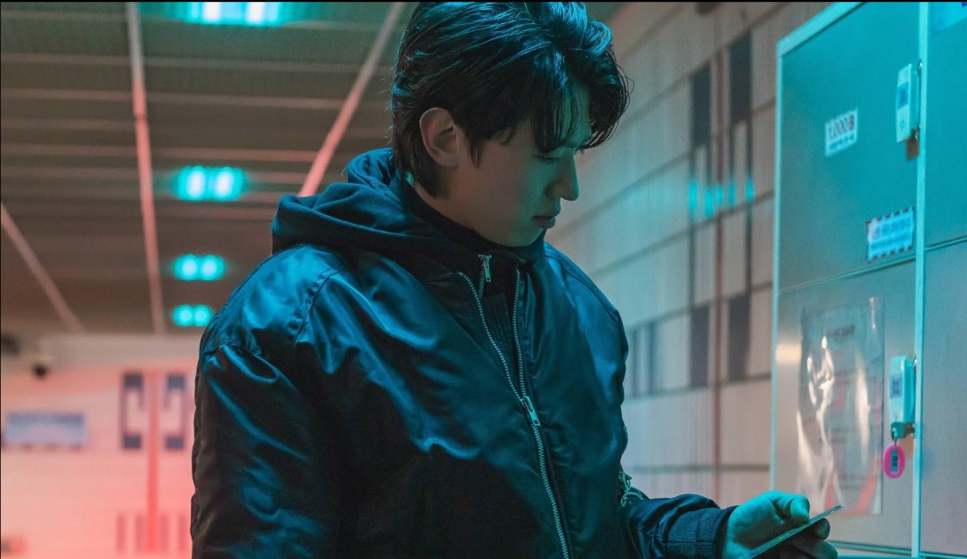 넷플릭스 영화 타로 덱스 김진영 스틸컷|어두운 조명 속에서 카드 봉투를 들여다보는 남성의 모습|불안과 공포가 교차하는 미스터리한 장면