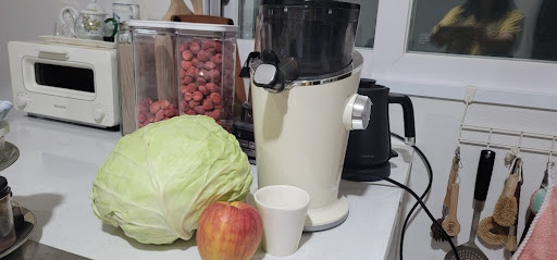 연두색 양배추와 사과, 주방 조리대 위에 놓인 착즙기와 컵, 아침 루틴 기록