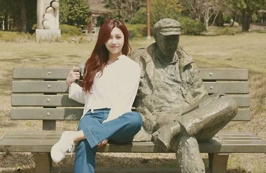 정은지-하늘바라기-뮤직-비디오의-한-장면으로-정은지가-중년-남성-동상이-있는-벤치에-나란히-앉아-있는-사진