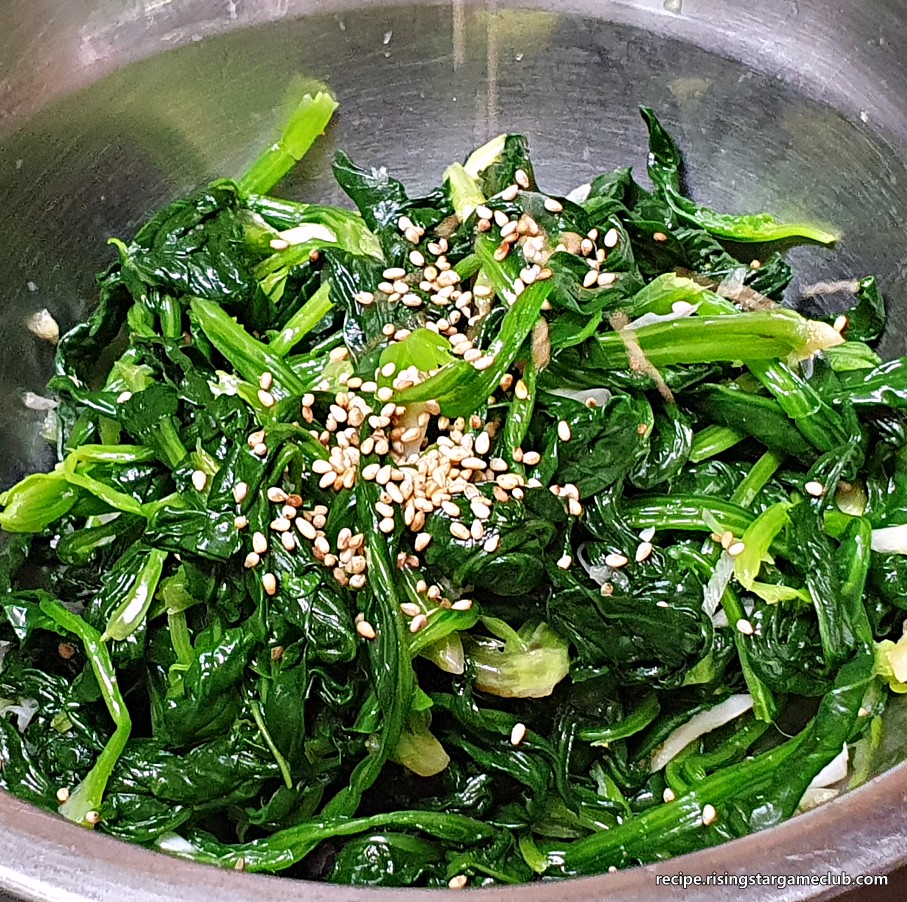 시금치나물 무침에 통깨를 솔솔 뿌려주는 사진