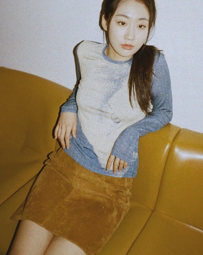 허회경이-갈색-스커트를-입고-갈색-쇼파에-기대-앉아-어딘가를-응시하는-사진
