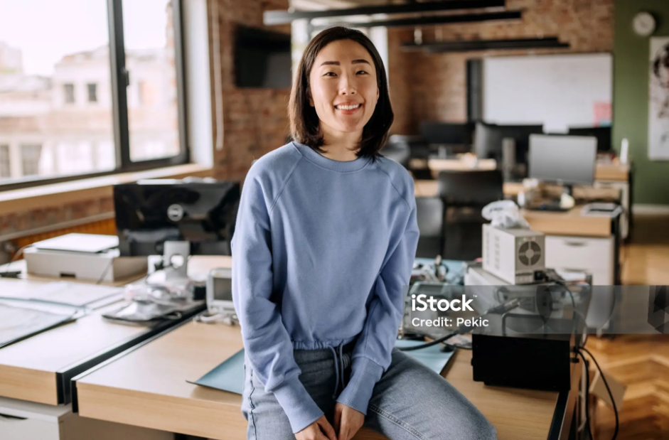 여성이 책상에 걸쳐앉아있는사진