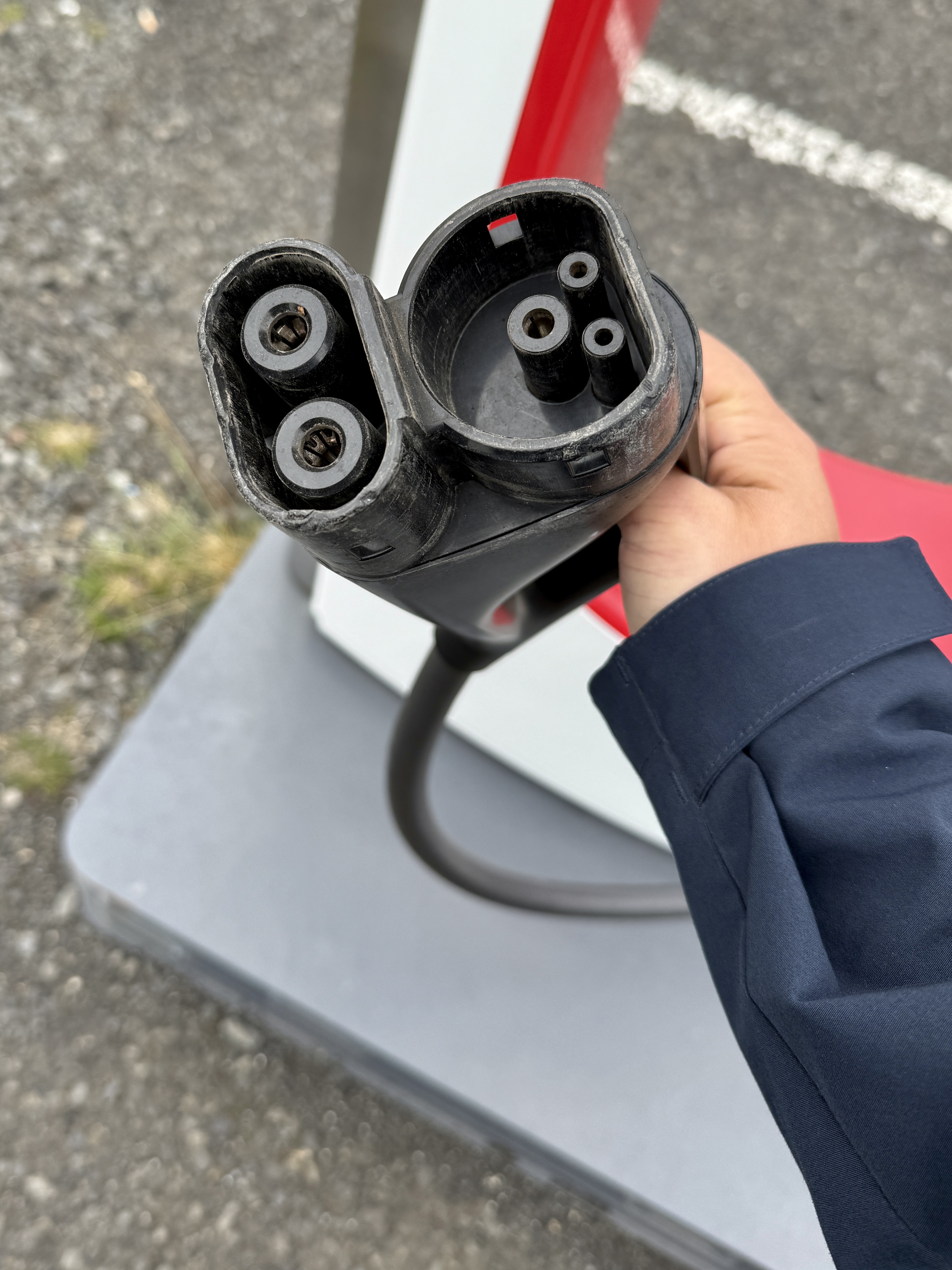 테슬라 슈퍼차저 충전기의 DC 콤보 타입 커넥터를 손에 들고 있는 모습