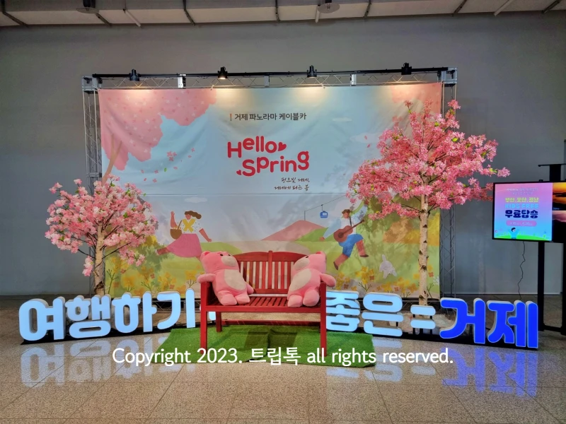 벚꽃과 현수막으로 꾸며진 거제도 케이블카 1층의 포토존 모습과 tv에 나온 무료탑승이벤트 안내