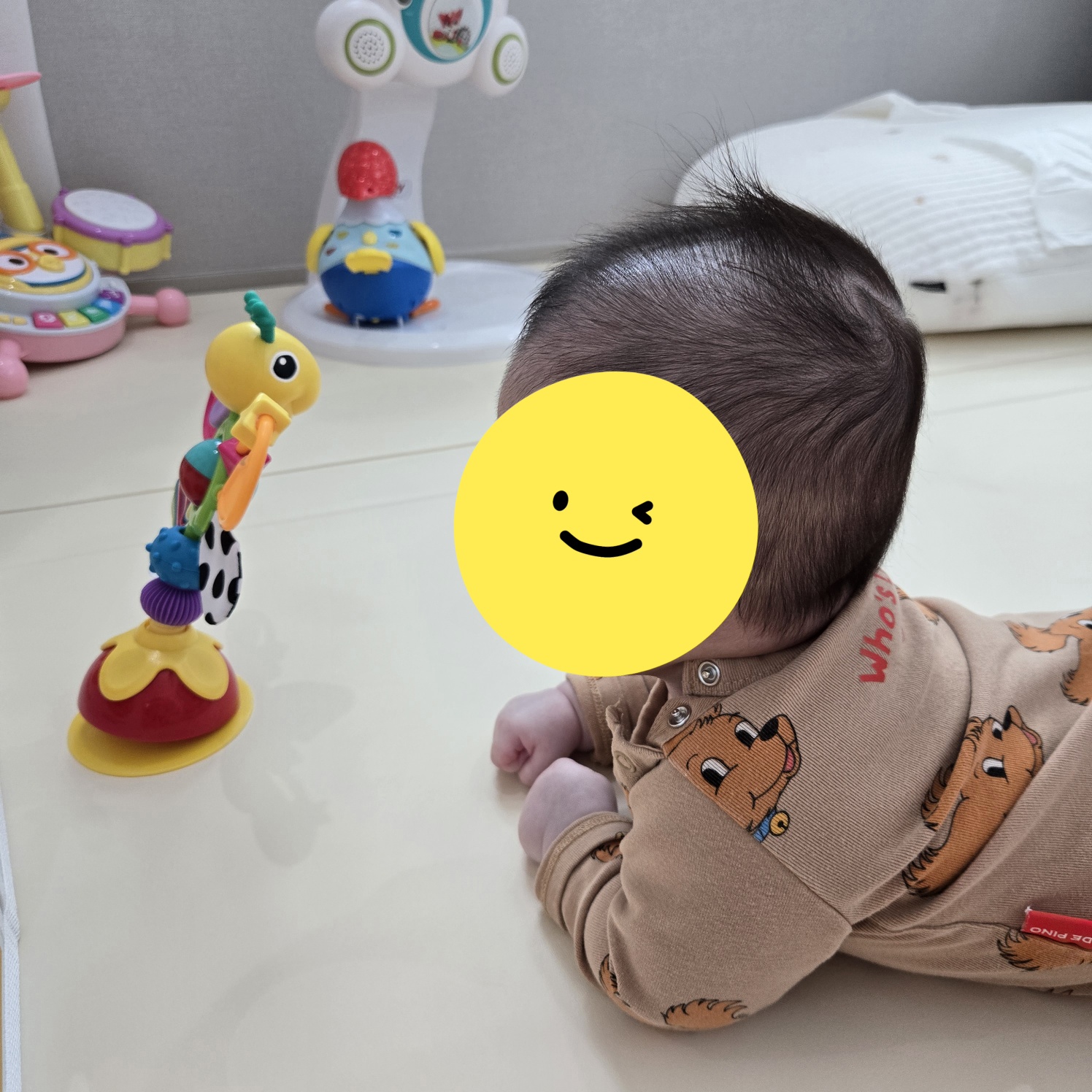 뒤집어서-장난감을보며-고개를-돌리는-아기의-모습
