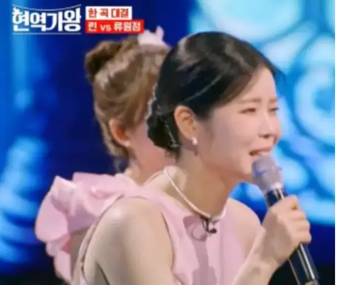 파란 무대배경 마이크를 든채 노래하는 가수 린