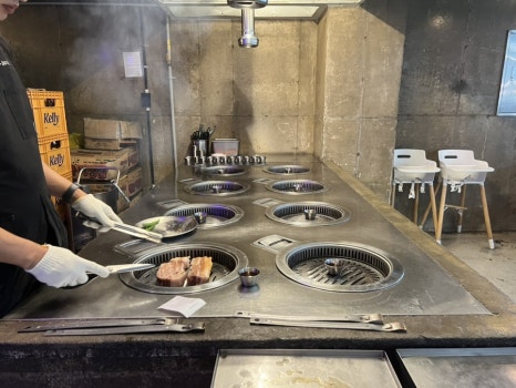 기장 삼겹살 맛집 부산댁에서 직원이 홀에서 직접 초벌구이를 해주는 모습, 숯불 위에서 고기가 익어가는 장면